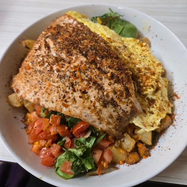 Mattie's Diner salmon dish with scrambled eggs, diced tomatoes, spinach, and roasted potatoes.