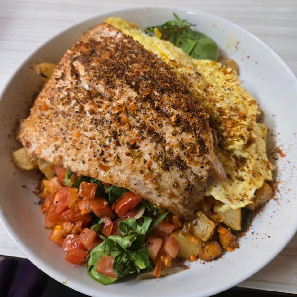 Mattie's Diner salmon dish with scrambled eggs, diced tomatoes, spinach, and roasted potatoes.
