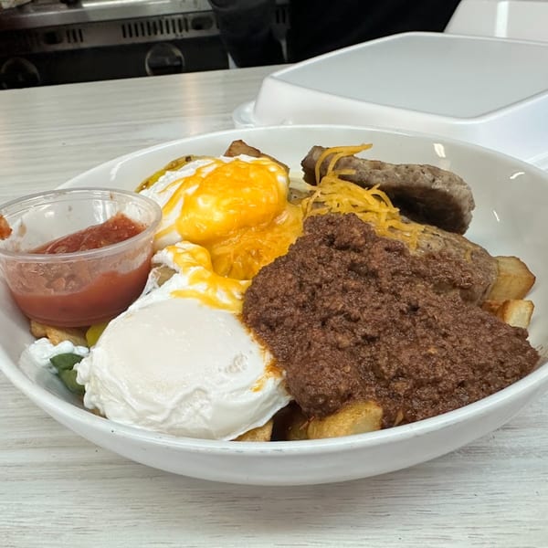 A Mattie's Diner breakfast bowl with eggs, sausage, chili, potatoes, and salsa.