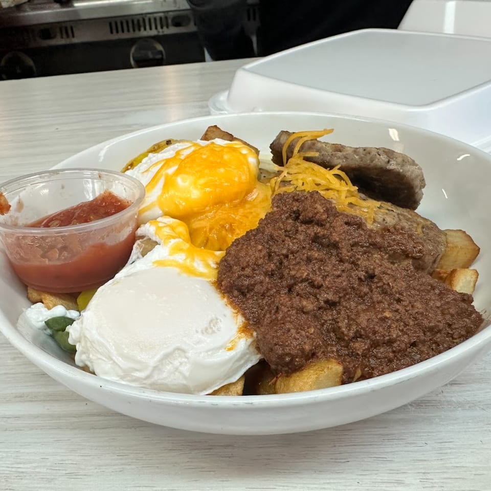 A Mattie's Diner breakfast bowl with eggs, sausage, chili, potatoes, and salsa.